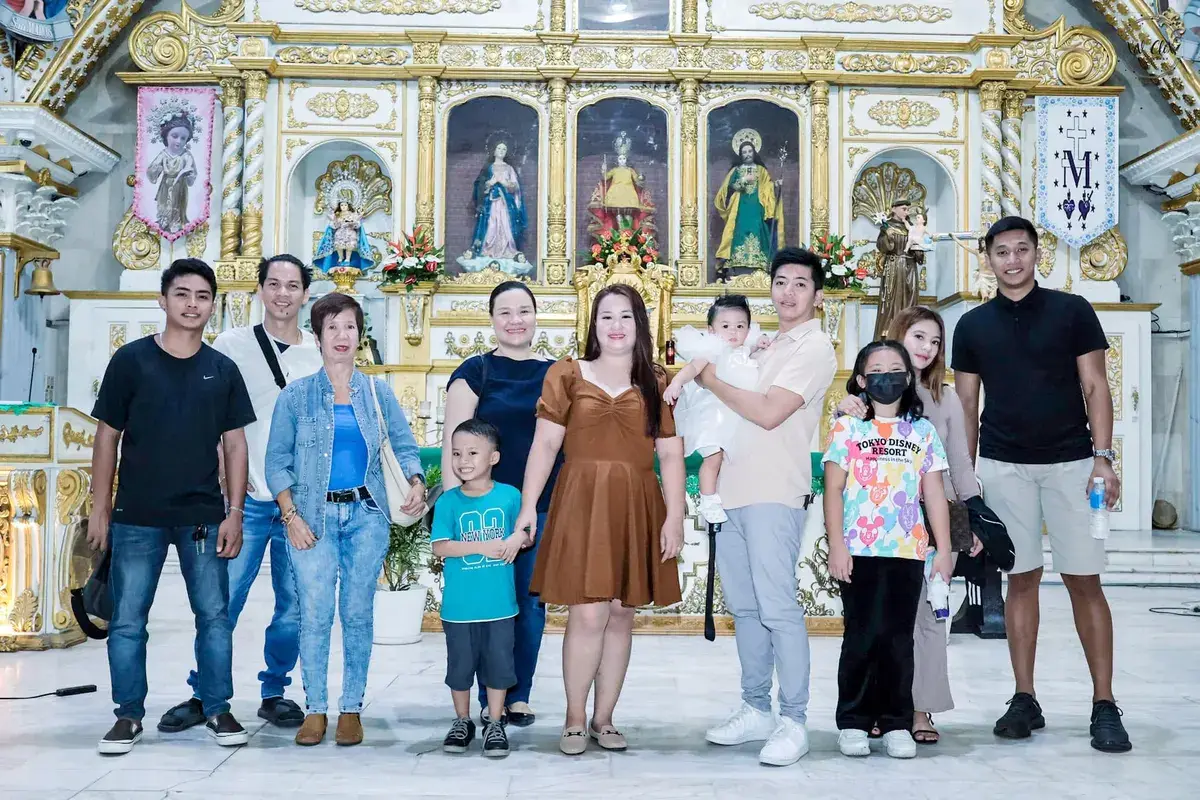 Extended family group photo with a baby in front of a gilded church altar