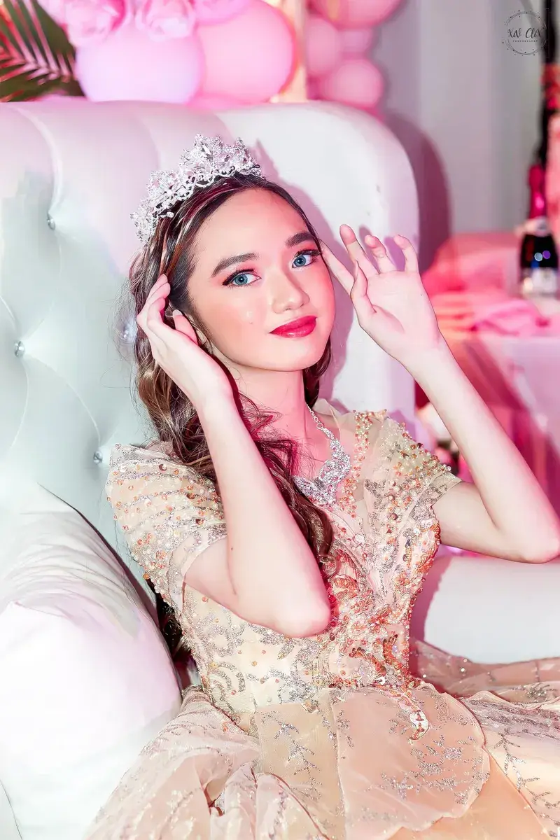 Debutante touching her hair while seated in a sparkling gown