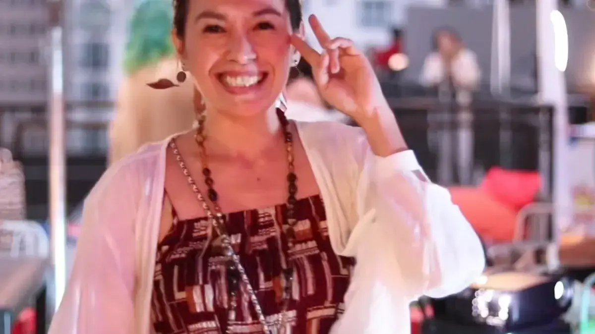 Smiling host in a red patterned dress at a rooftop company Christmas party
