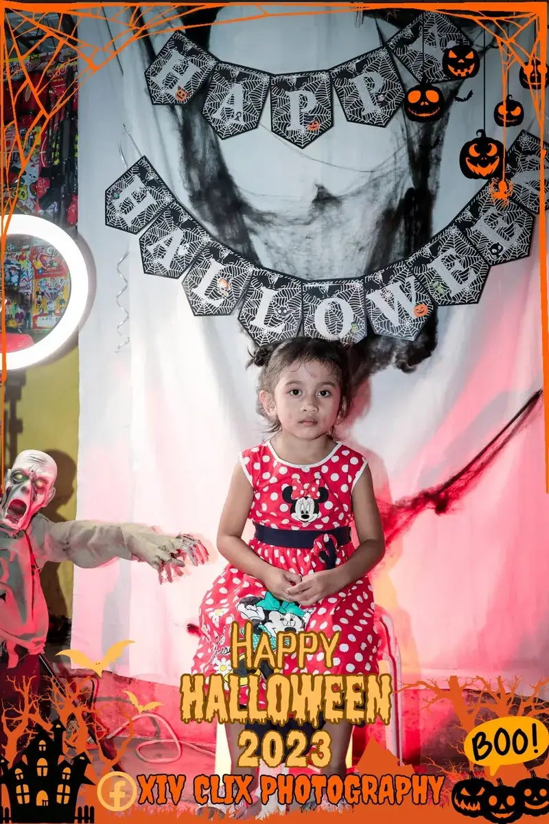 Toddler in a red polka-dot dress at a Halloween photo booth
