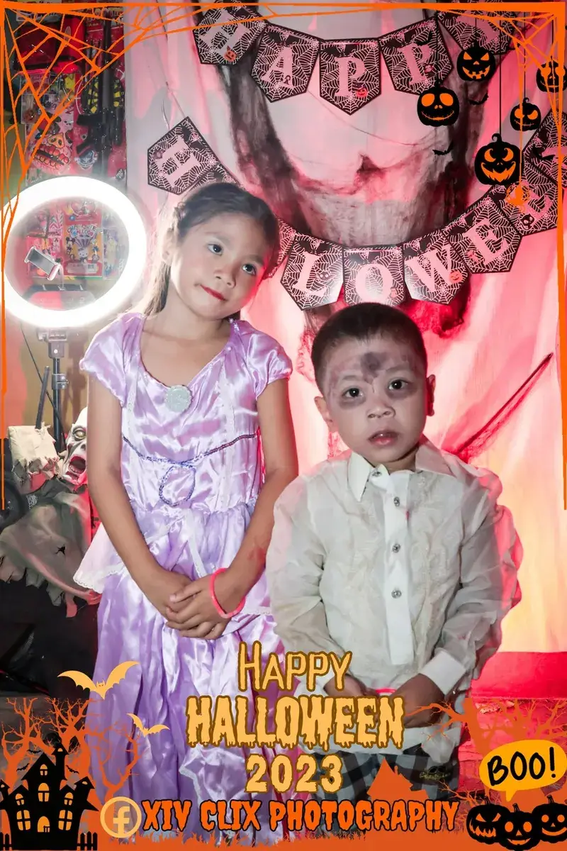 Two young children in costumes posing at a Halloween photo booth