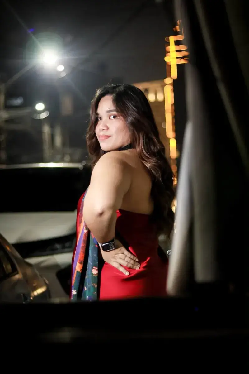 Woman in a red dress looking back over her shoulder on a night street