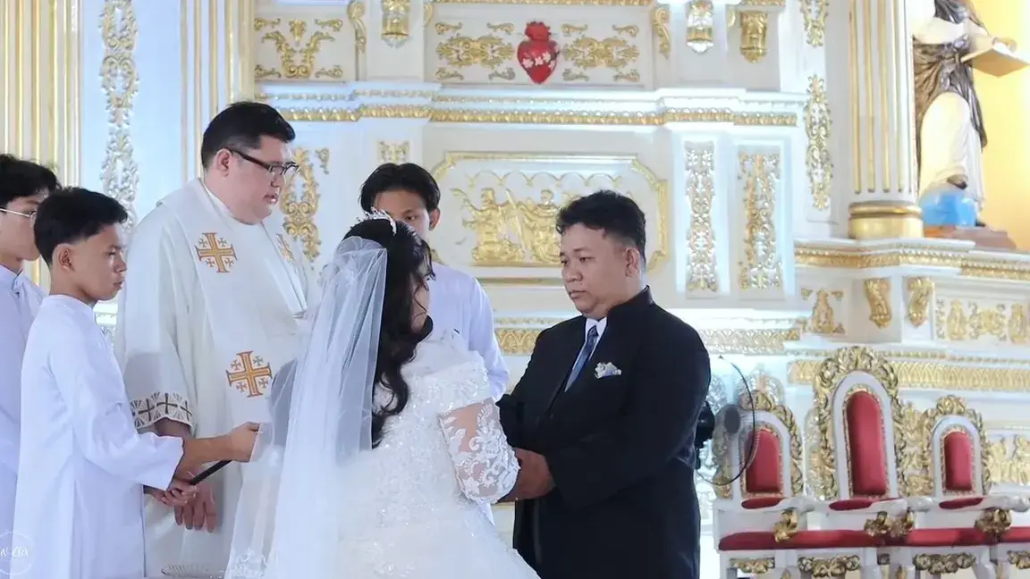 Priest leading the bride and groom through their vows at an ornate white and gold altar