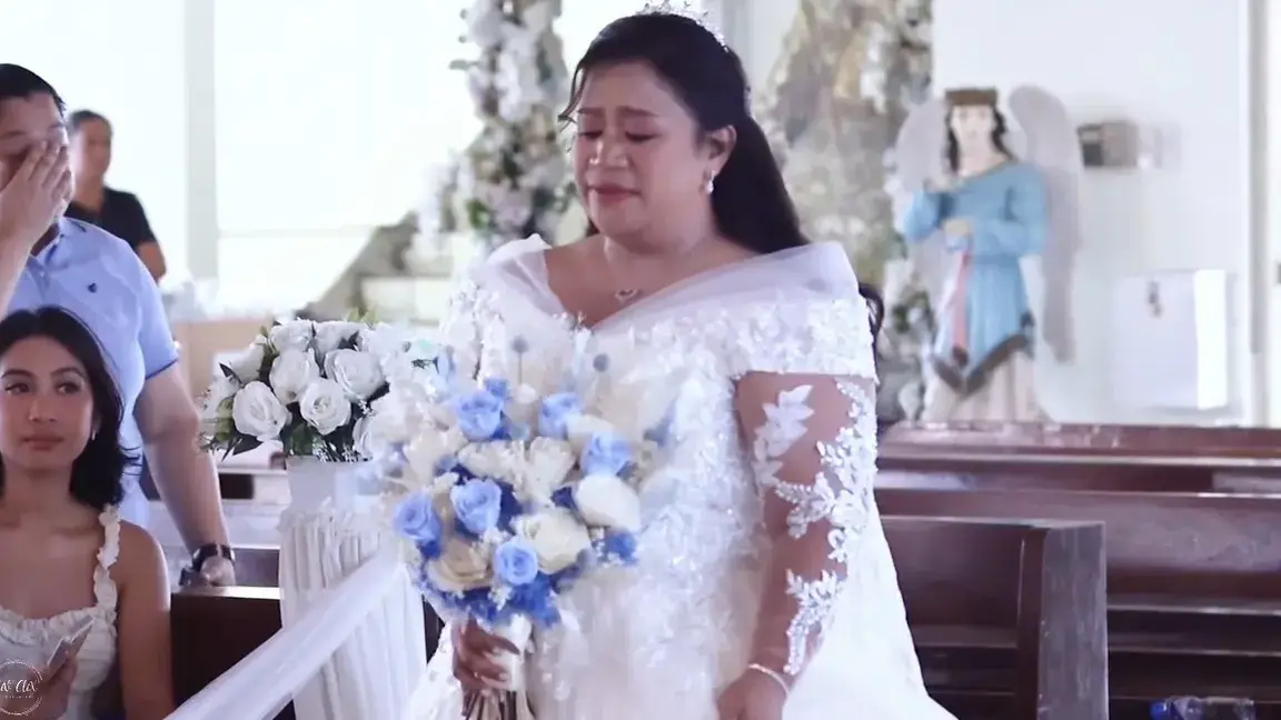 Bride in a lace gown holding a blue and white bouquet as she walks down the aisle